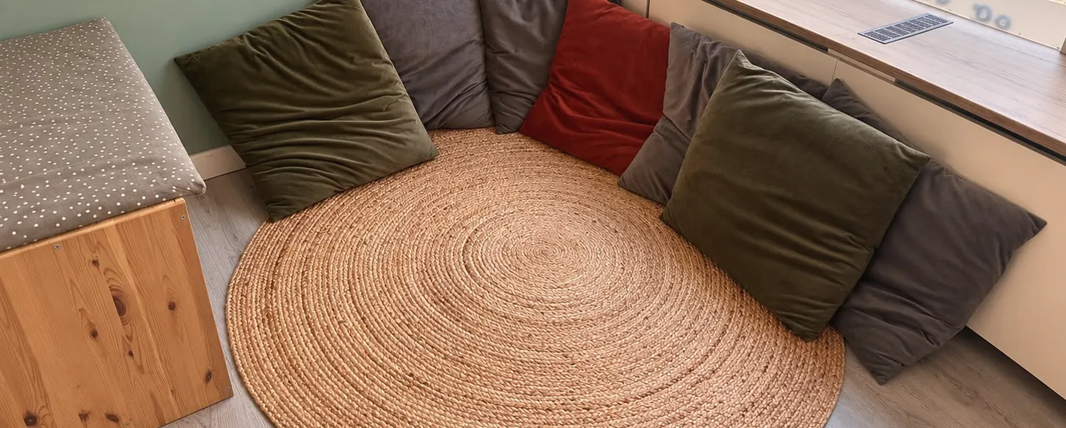 De leeshoek met een rond kleed en grote kussens bij het raam