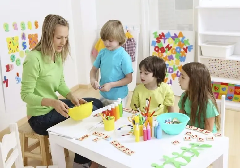 Pedagogisch medewerker knutselt met kinderen aan tafel